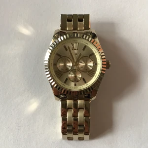 Guldig klocka  - En guldig klocka i väldigt bra skick! De tre små klockorna fungerar också. Allt som krävs är ett nytt batteri, sen är den som ny. Min handled är 16cm i omkrets, och den passar perfekt. Går att göra mindre, men tyvärr inte större