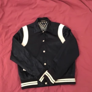 Tommy Hilfiger bomberjacka - Mörkblå Tommy Hilfiger jacka med vita detaljer och snyggt tryck över ryggen. Står storlek L men den sitter mer som en S/M. Använd men i bra skick!