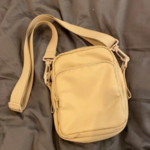 Axelremsväska - Köpt på Monki, endast använd ett fåtal gånger = mycket bra skick. Justerbart och utbytbart band. Rymmer mer än man tror (typ hörlurar, plånbok, mobil, litet anteckningsblock). Möts helst upp men kan frakta också, isf står köparen för frakten. Lägg bud i kommentarerna :)