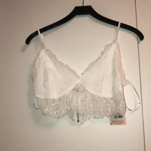 Vit bralette/topp - Oanvänd vit spets bralette från missguided. I sin originalpåse. Tyvärr för tunna band för min smak, därav säljes. Otroligt fin i modellen med spets undertill & dragkedja baktill. Strl 42