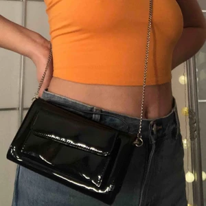 - Snygg liten Carin Wester väska i svart lack material. Avtagbar kedja, snygg att hålla i handtaget på själva väskan. I nyskick! Nypris:300kr. Rymmer telefon och dina kort tex. Frakt ingår💞