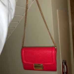 Röd väska - Liten axelbandsväska från H&M med guldiga detaljer, den är välanvänd men i bra skick! Frakt tillkommer❣️