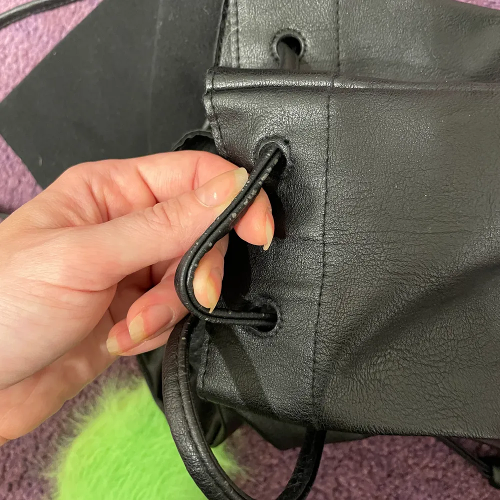 Svart ryggsäck från H&M. Skinnimitation. Storlek 30-10-32 cm.  På framsidan finns en repa som är nästan osynlig och små nötningar på snöret, som inte heller syns vid användning, annars fint skick. . Väskor.