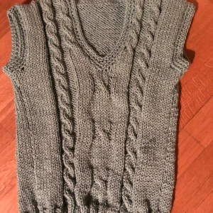 Grå stickad väst - Tillverkas för dig i Stockholm! Detta är en handgjord väst i storlek M. Om man vill ha den lite oversized rekommenderar vi att någon som är en S använder den. Om man vill ha den tightare funkar M. Vi tar även beställningar om din storlek inte finns.