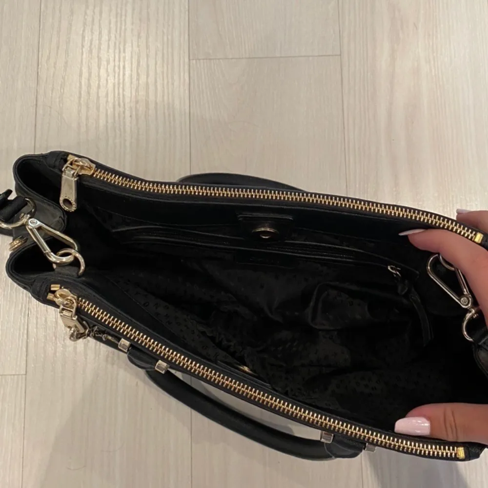 Purse/handbag from DKNY. Black with gold details. Never worn and in perfect conditions. Spacious inside, wearable over the shoulder with the longer strap or held in the shorter handles. Shipping is included in the price!💞. Väskor.