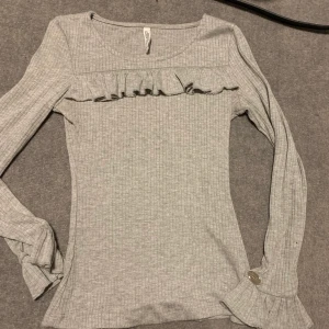 Tröja  - Långärmad grå tröja med volanger.🥰