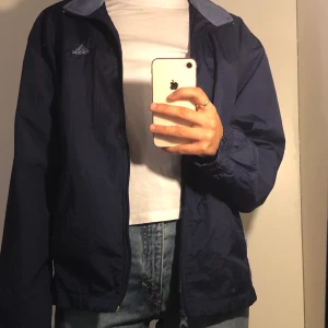 Adidas vintage vindjacka! - Hej vi säljer en schysst vindjacka från adidas i storlek L, men passar er som har storlek S också. Den har en marinblå/ljusblå färg, två fickor och normal passform. I väldigt fint skick. Skriv i dm du skulle vilja se mer detaljerade bilder :)
