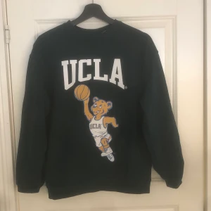 H&M UCLA sweatshirt - En snygg mörkgrön sweatshirt med snyggt tryck!! Säljer då jag inte använder den längre!! Mitt pris är inkl frakt🤪 Kan gå med på att sänka pris vid snabb affär☺️