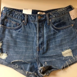  - Oanvända korta jeansshorts med avklippt kant och slitage. 