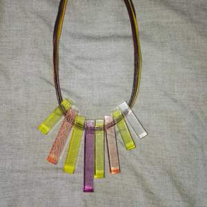 Halsband i kort modell med hänge i olika färger.