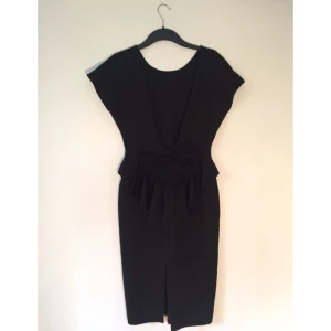  - Elegant klänning, helt slät på framsidan, rosett på baksidan och djup ringning i ryggen. Märke okänt, vintagefynd. 