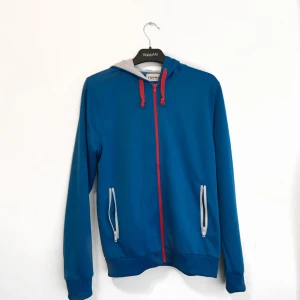  - Korallblå hoodie med röd dragkedja i fint skick!