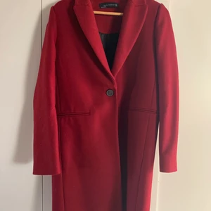 Zara ullkappa strl M - Fin ullkappa i mörkrött från Zara. Strl M men passar både en 36:a och 38:a. Knäpps med en knapp. Använd 2 gånger så i mycket fint skick. Materialbeskrivning: 75% ull 25% polyamid