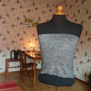 Silverglittrigt linne utan axelband - Detta fina linne utan axelband från Monki säljes då det inte längre används. Hålls uppe med hjälp av en gummislinga högst upp i kanten. Passar S och M. En fd favorittröja! Fint skick!