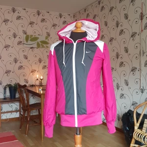 Nike-löparjacka säljes - Denna nike-löparjacka säljes då den inte blivit använd på flera år. Färgen är inte lika rosa som på bilderna utan mer lila. Passar nog bäst på S även fast det är en M. Två fickor utan dragkedja i sidorna.