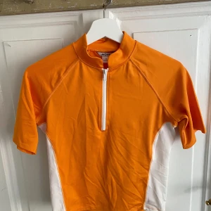 VIT/ORANGE TOPP - Vit/orange topp från MONKI. Aldrig använd och prislapp finns kvar. Nypris: 180kr. Möts på Södermalm och vid frakt står köparen för kostnad!