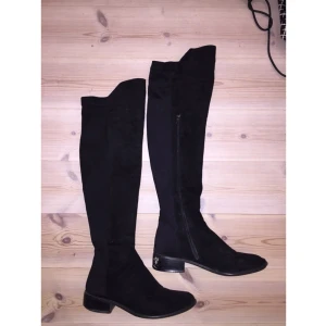  - Lårhöga skor från Nelly som kostade 699kr nya. Som ni ser på bilden är dem i använt skick men jag tror man kan använda någon svart skokräm för att få bort det vita på klacken som skrapats upp. Något som inte syns när man väl har på sig dem. 
Resår i bak som gör att de sitter tight och bra runt låret. 

Kan posta men då står du för frakten!