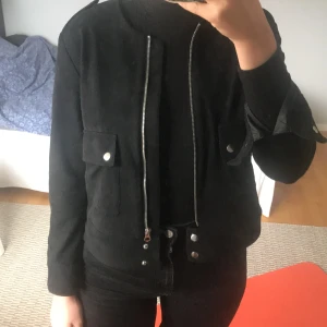  Svart jacka i mockaimitation - En tunnare jacka i svart mockaimitation med silverdetaljer. Fint skick och väldigt snål använd. Säljer då den inte kommer till användning. 
