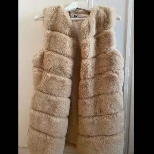 Pälsväst beige - Pälsväst, ca 100cm över bysten och ca 75cm lång. Den är i storlek S/M och använd cirka 3 gånger. Nypris: 650kr