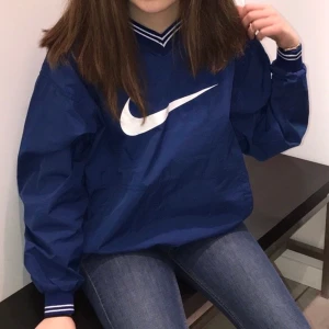 Nike tröja - En vintage Nike tröja i windbreaker material likt en jacka. Jättefint skick med en ficka på framsidan. Storlek XL(barn) vilket passar bra på mig som är XS, alltså lite liten i storleken. Frakt tillkommer:)