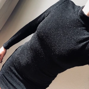 Skimrande klänning  - Figursydd klänning från DRY LAKE som skimrar i silver. Nopprig här och där men det tas enkelt bort och syns då ej när en har den på sig. Långa armar, polo och slutar mitt på låret. Sitter snyggt med dold dragkedja i ryggen. 