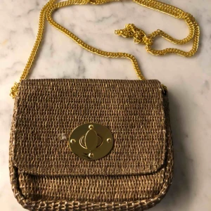  - Liten väska i guld med guldkedja. Kan böras crossbody