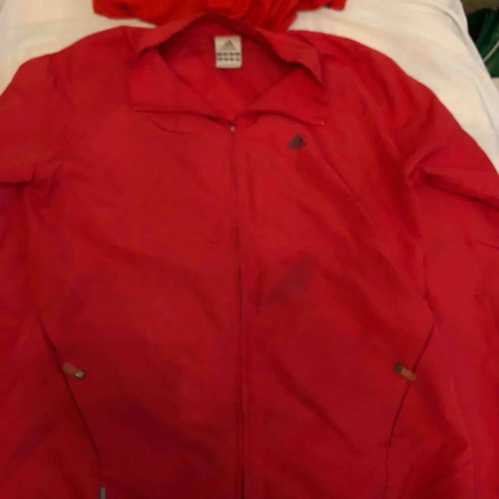 Adidas jacka i rött. En fläck på framsidan av jackan annars i bra skick. Frakt ingår. Jackor.