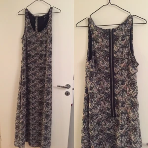 - Vacker lång sommarklänning med små blommor. Dragkedja som går ner en bit på ryggen.