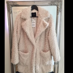  - Helt ny jacka med lappen kvar. Otroligt mysig och fin. En knapp fram till att stänga den. Inga märken eller liknande, väldigt fint skick. 