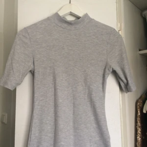  - Grå tröja med turtleneck från Nelly trend sparsamt använd. Slutar precis där första bilden skär. Ärmen slutar på halva överarmen 