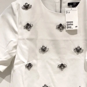  - Superfin kortärmad topp med ”kristall”applikationer på framstycket. Oanvänd med lappar kvar (behöver uppenbart strykas då den legat orörd i garderoben haha). Bra kvalité på tyget, ej stretchigt.