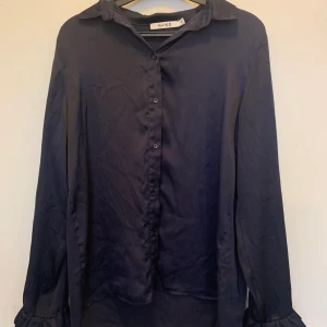 Marinblå blus med volanger vid armen  - Säljer denna vackra blus från nakd. I storlek xs. Men den passar även en s/m skulle jag säga. Den är väldigt skön. Skriv för frågor. Köparen står för frakten.