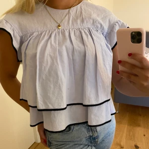Söt ljusblå blus - Söt ljusblå blus från ZARA med fina volanger och svarta detaljer! 😍 Finns inte att köpa i deras sortiment längre, men denna är i nyskick! 🤩 kan frakta!