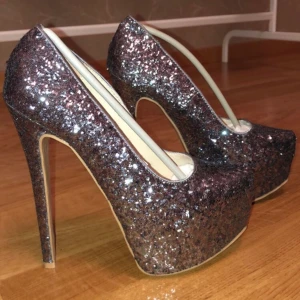Glittriga klackskor strl. 37 - Använda under endast en natt. Storlek 37. Höjden är jag osäker på då jag ej minns men tror 26 cm? Köpta från Bubbleroom.
