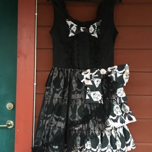  - Söt klänning i svart/rosa med tryck av pudlar och överlager av chiffong, från kända japanska märket h.Naoto Frill. Oanvänd, med lappar kvar. Justerbar i ryggen via snörning, bör passa en midja på ca 60-80 cm. 