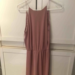  - Smutsrosa klänning som går till straxt över knäna. Armlös, låg rygg med spets