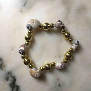  - Stretchigt band, gjort av äkta snäckor. Frakten kommer på 9kr och är inräknad i priset. 