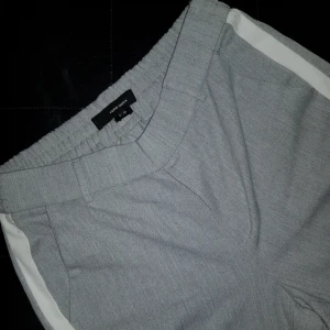  - Säljer gråa kostymbyxor i väldigt fint skick. Sparsamt använda max 2-3 gånger, till billigt pris. (Säljer för att de har blivit för små) Finns en vit, jämn rand på båda sidorna om benen. Finns två fickor vid höften till. Längden (på byxbenen) är 87cm från kant till kant (höft till fot).