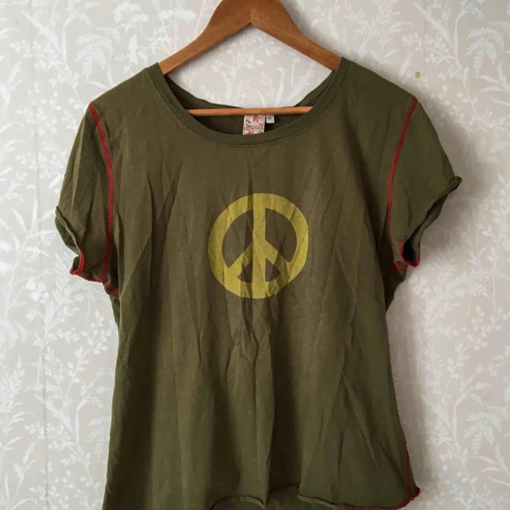 Retro grön t-shirt. Detaljer i form av röda sömmar och peacemotiv. Står XL i den, men passar bra på en M. Kan frakta eller mötas upp I Stockholmsområdet.. T-shirts.