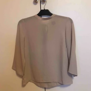  - Säljer en beige blus från Gina tricot i strl 36. Trekvartsärm och med knytning i bak i ryggen. Tunn i materialet. Endast använd fåtal gånger så i mkt fint skick. Bra i storleken! Köparen står för frakten.