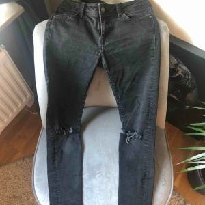  - Svarta jeans med egen klippta hål vid knäna. 