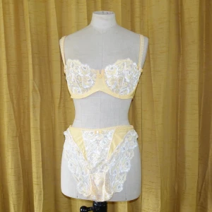 Gul-vitt set - Så gulligt set. Gult med vita detaljer, mycket spets och söta rosor och rosetter. Aldrig använd annat än till visningsex i skyltfönster. Frakt ingår i priset.