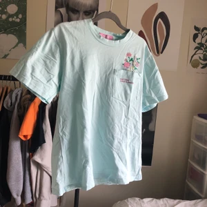 ”Just take these flowers” pastell tröja - Megagullig t-shirt från kokopie, Turkos/pastellblå med en liten ficka med gulligt tryck. Bra skick, storlek s. köparen betalar fraktkostnad🌸💗💘💘💞💕