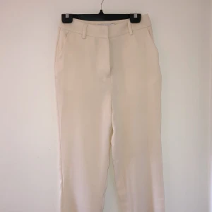 Benvita byxor NaKd - Härliga sommarbyxor från NaKd perfekt till både fest och vardag! De är oanvända och säljes pga för långa för mig. Jätteskönt material! Köpt för 200 kr, jag säljer för 85kr. Köparen står för frakt🥰