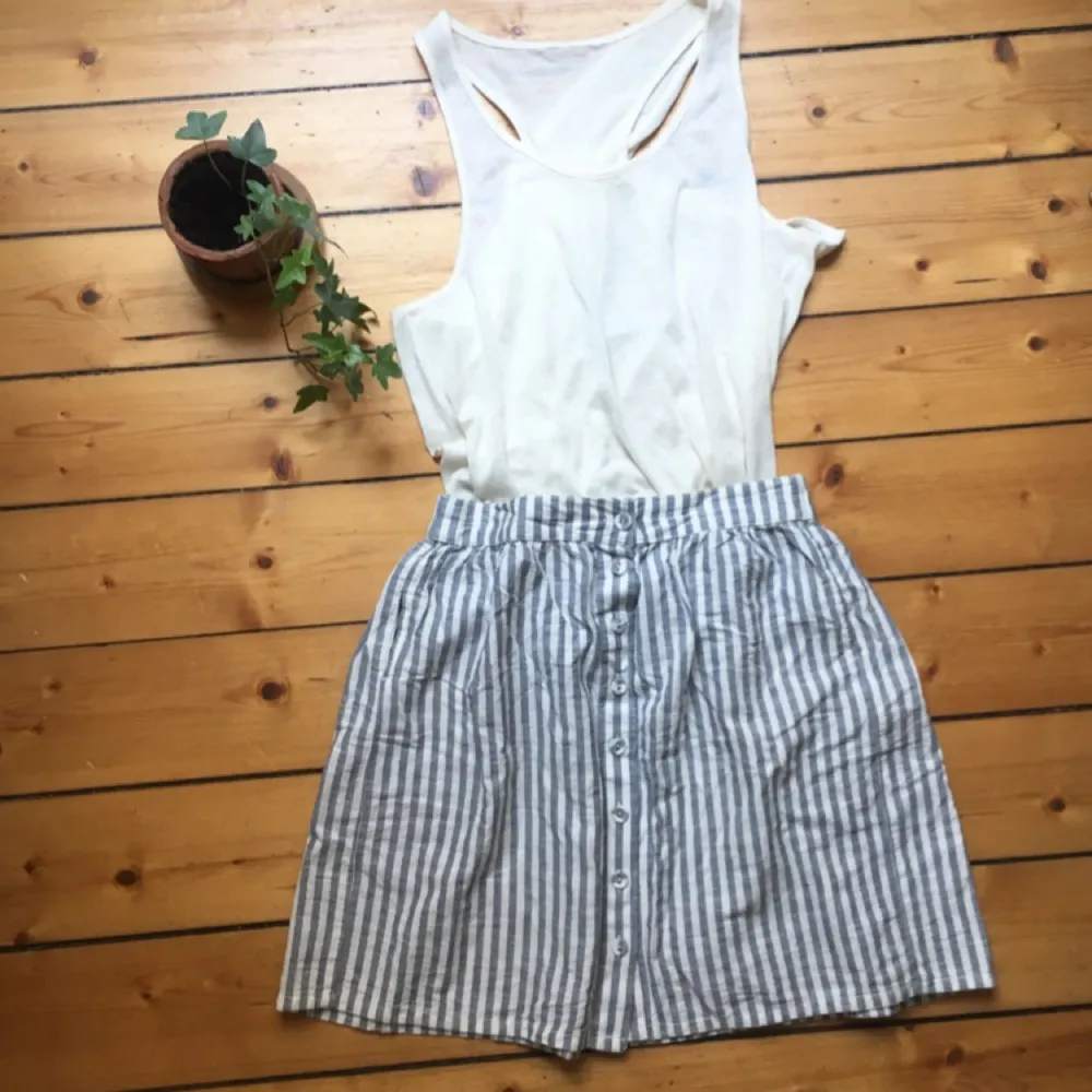 En grå och vit randig kjol med små knappar framtill. Tillverkad i bomull och har resor i midjan! Fint skick! 🌟. Kjolar.