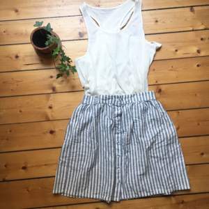 En grå och vit randig kjol med små knappar framtill. Tillverkad i bomull och har resor i midjan! Fint skick! 🌟