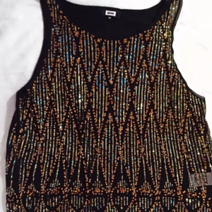  - Svart topp med paljetter i silver, guld och brons. Köpt på BIK BOK i M och är endast använd en gång