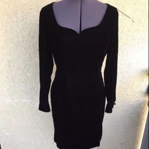 - Fin svart vintageklänning i sammet. Köpt från Beyond  Retro. Men aldrig använd.  Passar en 36:a eller liten 38:a.  Modellen slutar ovanför knäna.  Fin knäppning kring handleden med originalknappar. 