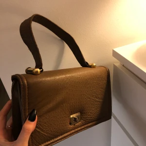 Populär brun axelväska - Brun axelväska med bra utrymme. Har aldrig kommit till användning, guldiga detaljer. Osäker på märke dock. Priset går att disskutera