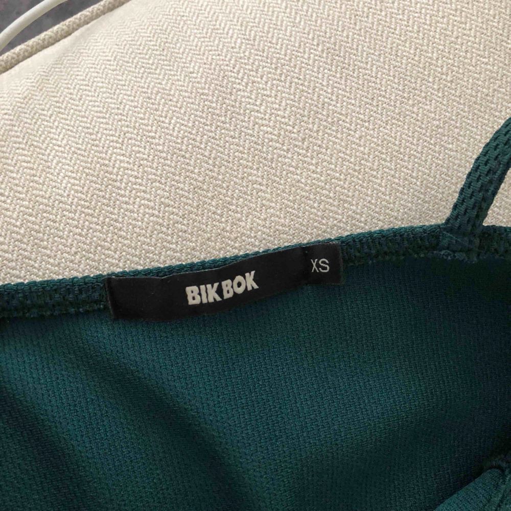 Snyggt linne i mörkgrön färg, med ”BH” på utsidan,i kort modell. Toppar.